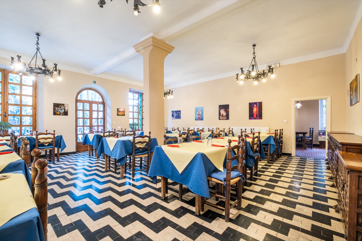 Sala luminosa di Govinda con tavoli apparecchiati e opere alle pareti